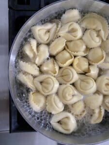 Boiling tortellini before sauteeing.