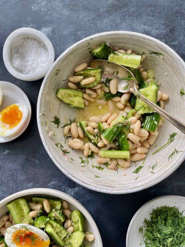 this shows the smashed cucumber and bean salad being tossed